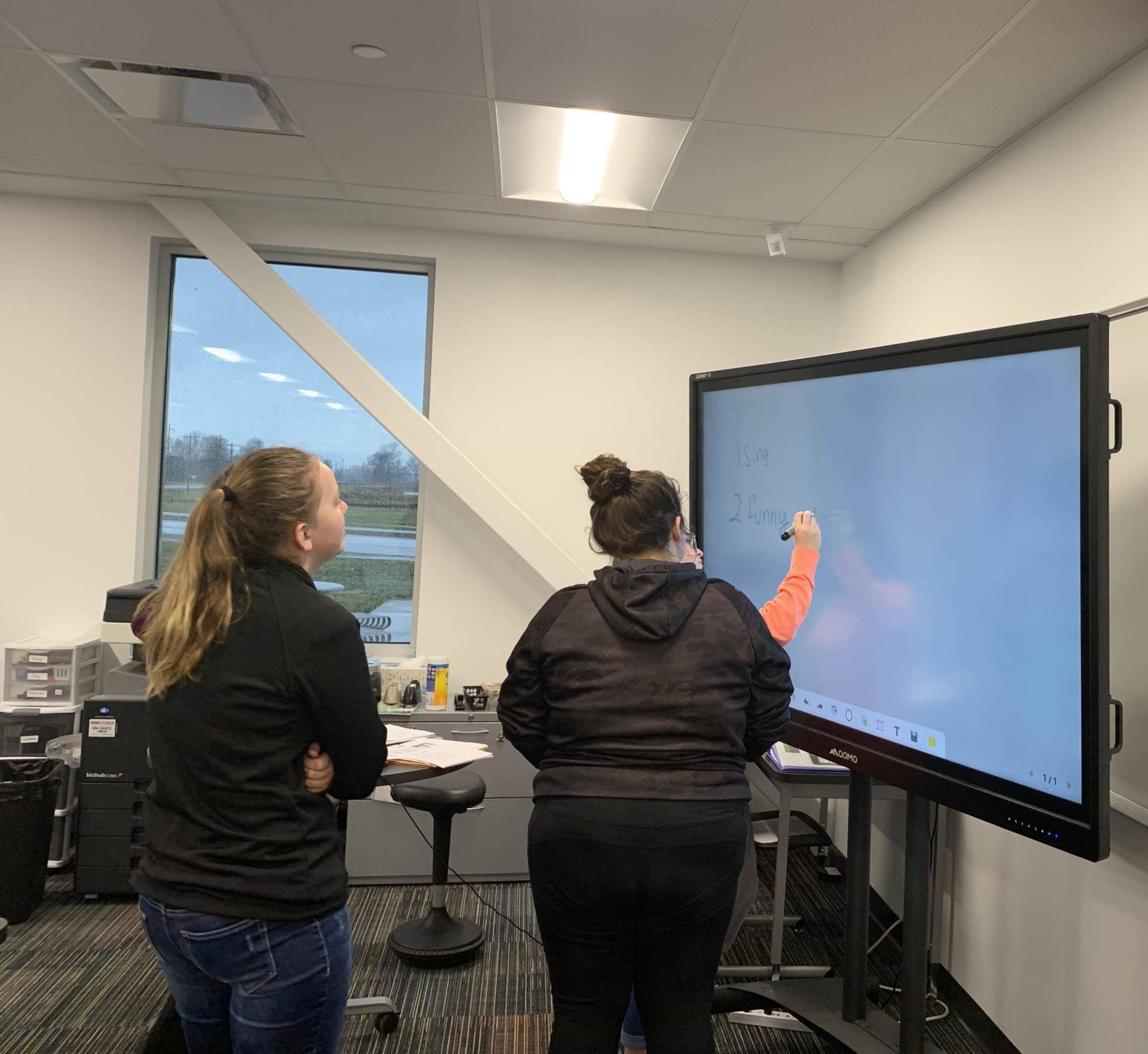 Students writing on the smart board.